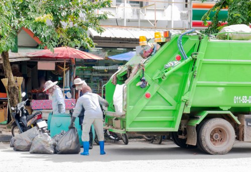 Low-emission delivery van and crew loading a skip
